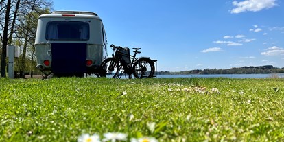 Campingplätze - Wasserspielplatz - Bad Endorf - Eriba Wohnwagen am Seestellplatz mit Fahrrädern und Gänseblümchen - Camping Stein