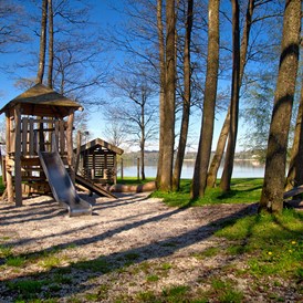 Campingplatz: naturbelassener Spielplatz mit hohen Bäumen, direkt am See - Camping Stein